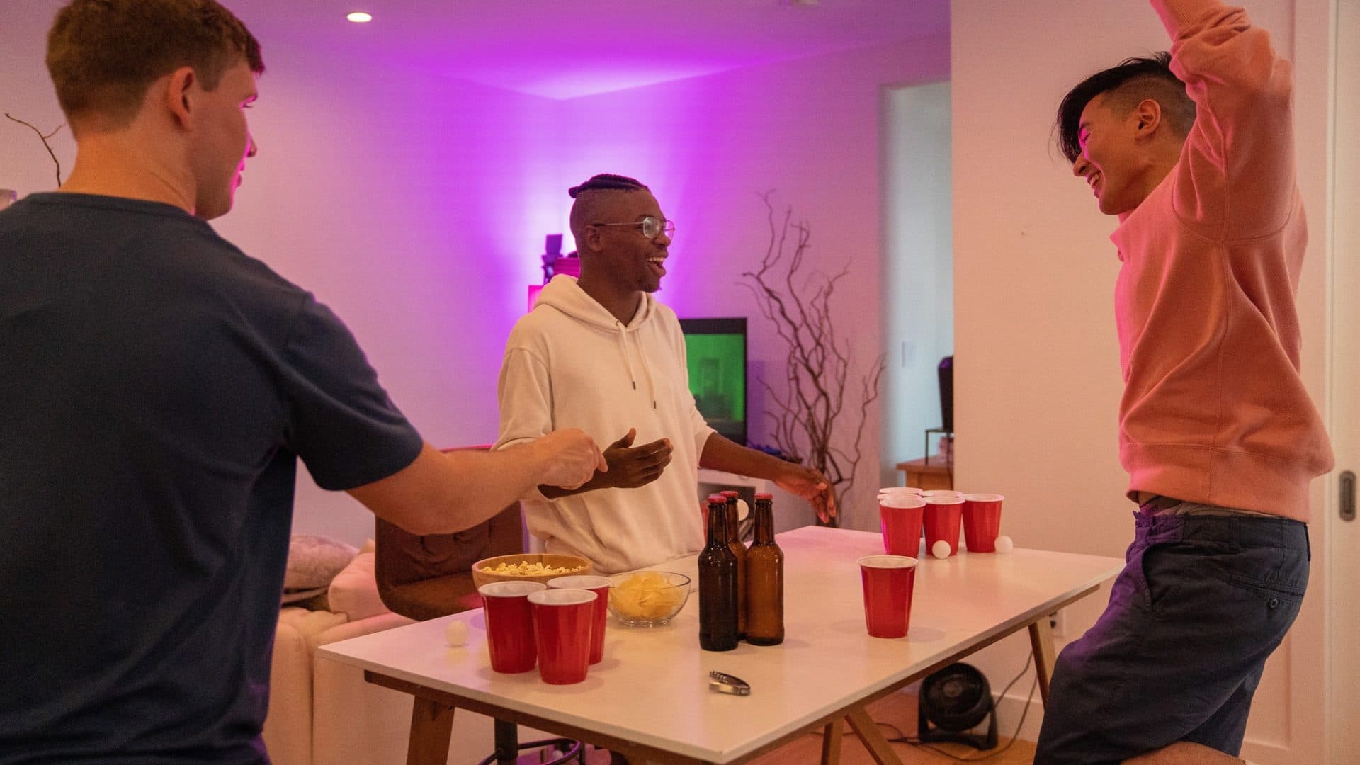 Three young renters laughing around a table during a get-together in their apartment